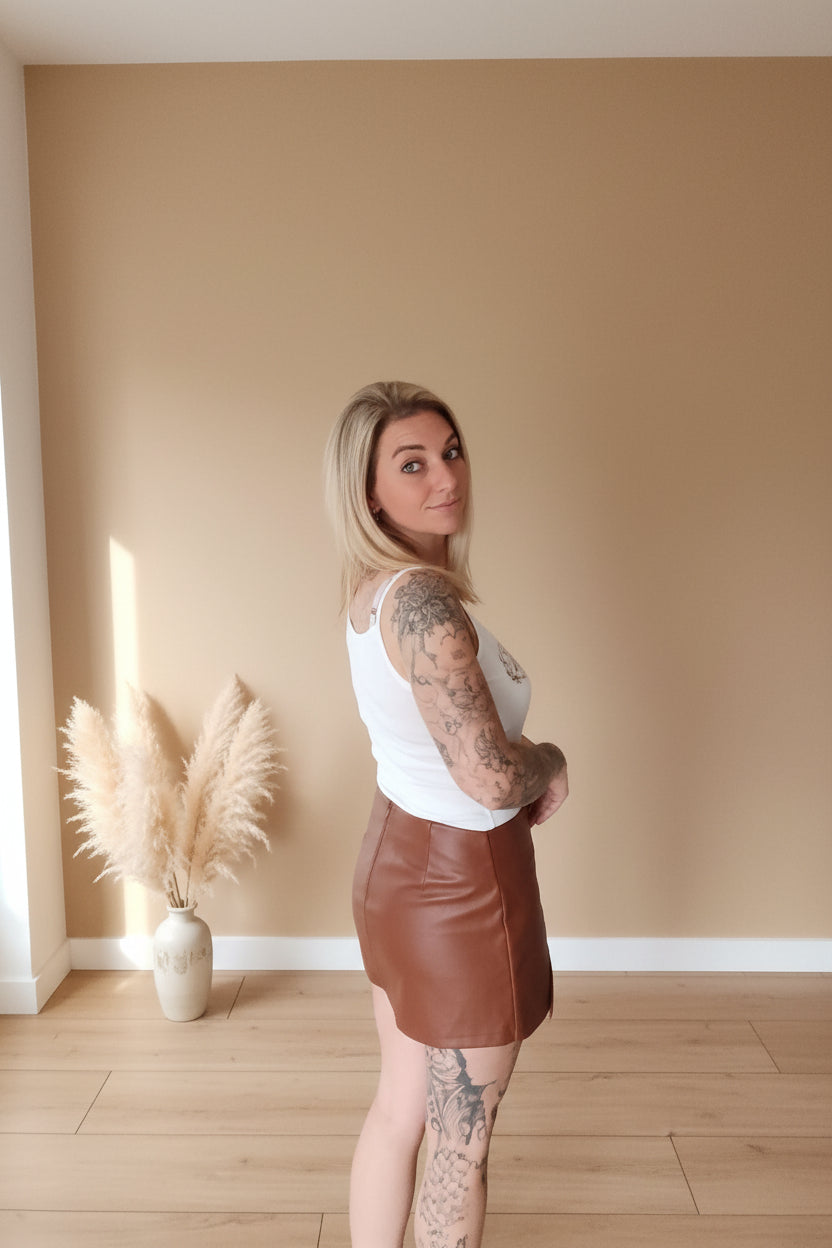Boho-Luxe Look: Eleganter weißer Tanktop und brauner Minirock aus Leder.