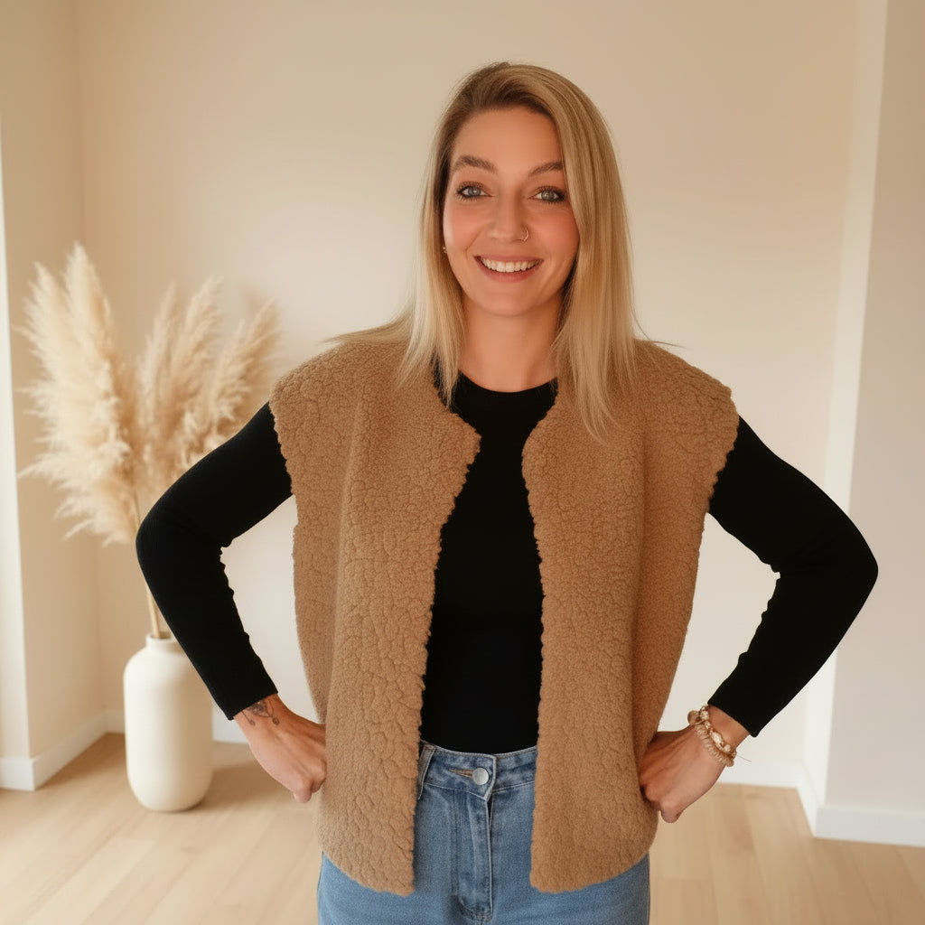 Khakifarbene Teddyfell-Weste für Damen im offenen, ärmellosen Design, kombiniert mit schwarzem Oberteil und Jeans