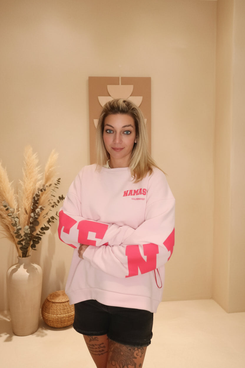 Namasté Oversize Sweater Pink – Frontansicht verschränkte Arme, pinker Namaste-Print auf der Brust