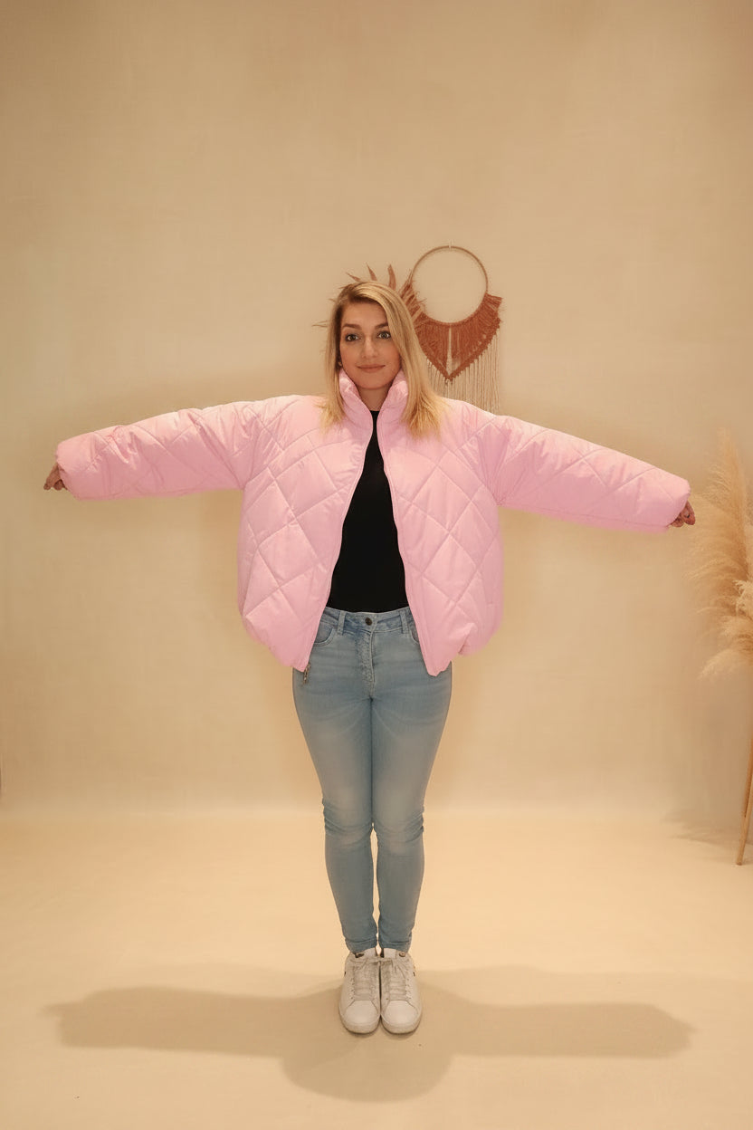 Frau in rosa gesteppter Boho-Luxe Jacke aus Nylon und hellblauen Jeans.