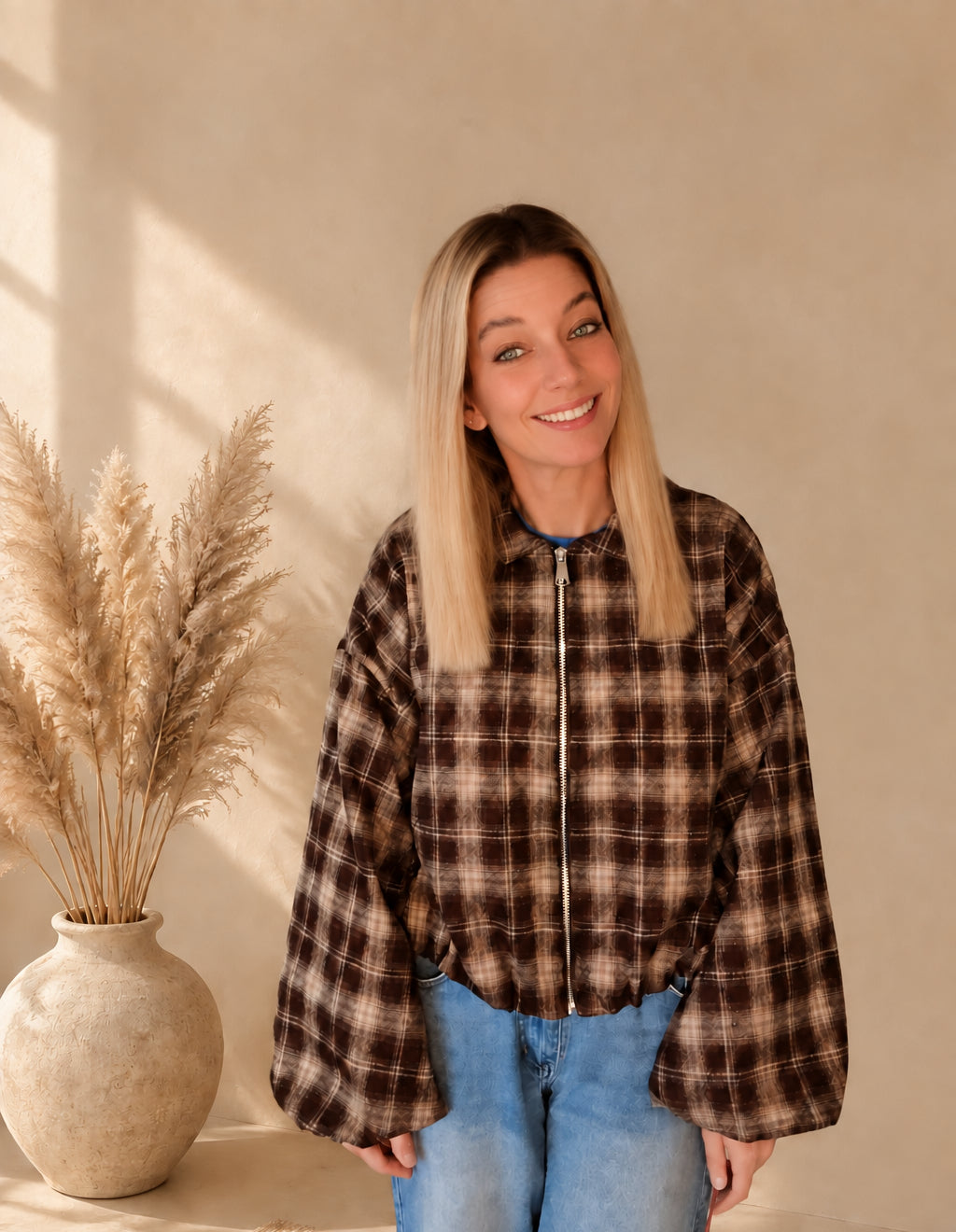 Frontansicht einer geschlossenen karierten Damenjacke in Dunkelbraun und Beige mit Kragen und Reißverschluss.