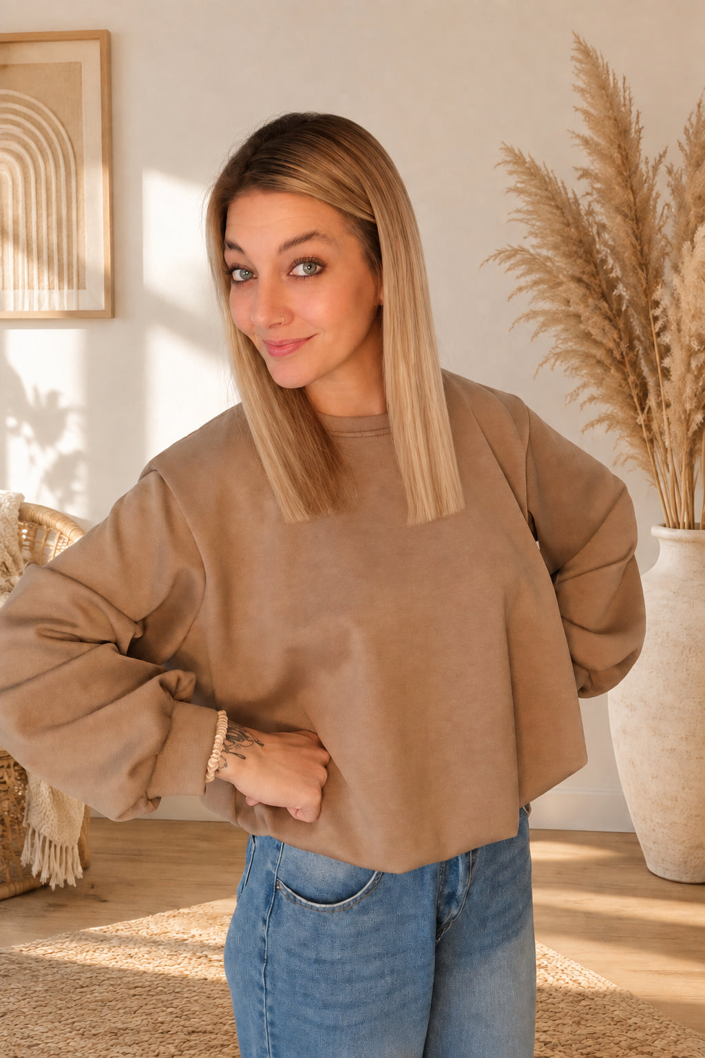 Damen-Sweatshirt in Taupe mit Rundhalsausschnitt und weiten Ärmeln, am Model in schräger Vorderansicht mit blauer Jeans.