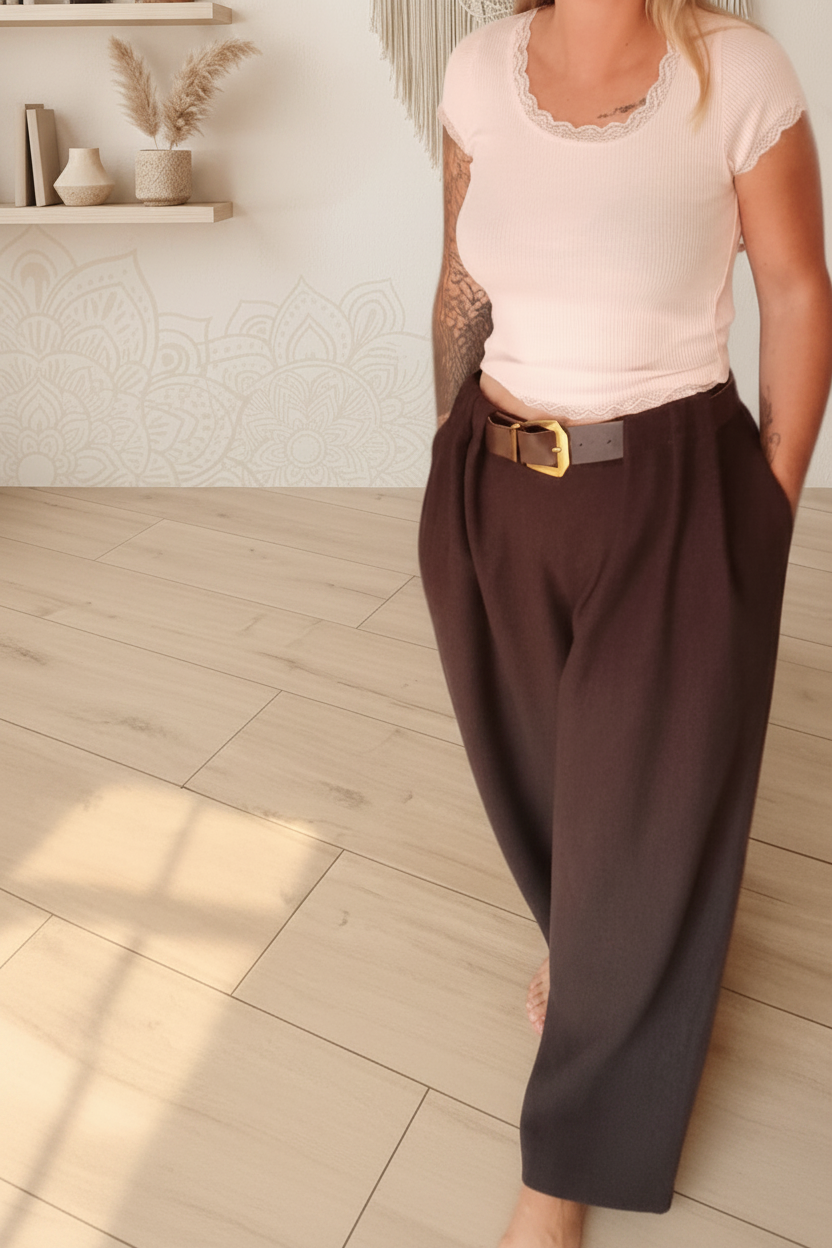 Boho-Luxe Look: Hellrosa Rippstrick-Top und dunkelbraune Stoffhose mit Gürtel.