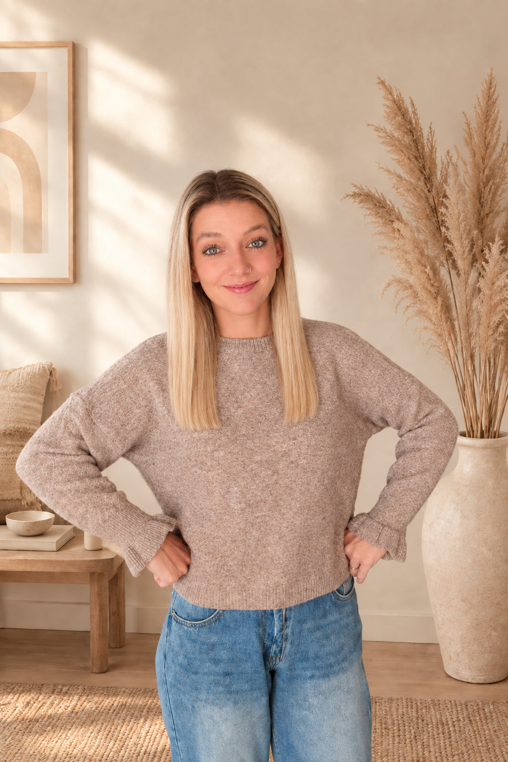 Model trägt einen taupefarbenen Damenpullover mit Rundhalsausschnitt und geripptem Saum, beide Hände an der Hüfte.