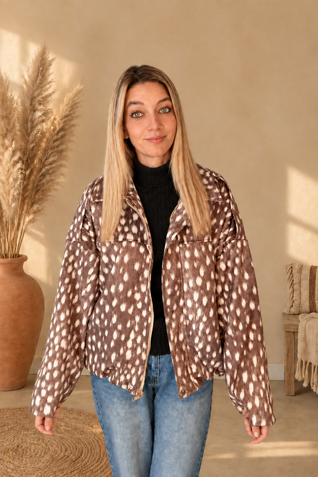 Braune Damenjacke mit cremefarbenem Fleckenmuster, Kragen und Reißverschluss, offen am Model mit gesenkten Armen.
