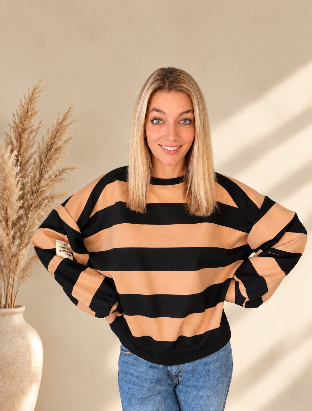 Gestreiftes Damen-Sweatshirt in Camel und Schwarz mit Rundhalsausschnitt, weiten Ärmeln und hellem Ärmelpatch.