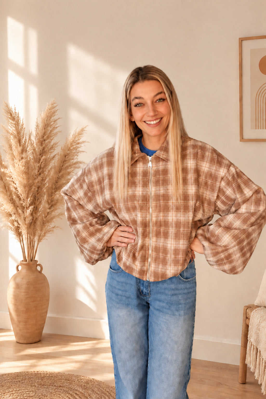 Karierte Damenjacke in Braun und Creme mit Kragen und Reißverschluss, frontal mit einer Hand an der Hüfte.