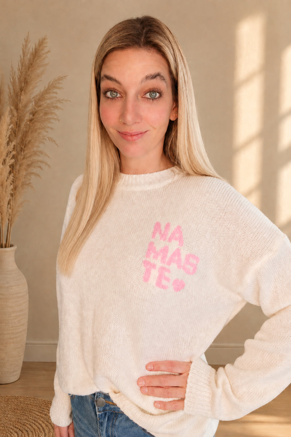 Cremeweißer Strickpullover mit rosa Namasté-Brustprint und Rundhalsausschnitt, am Model.

