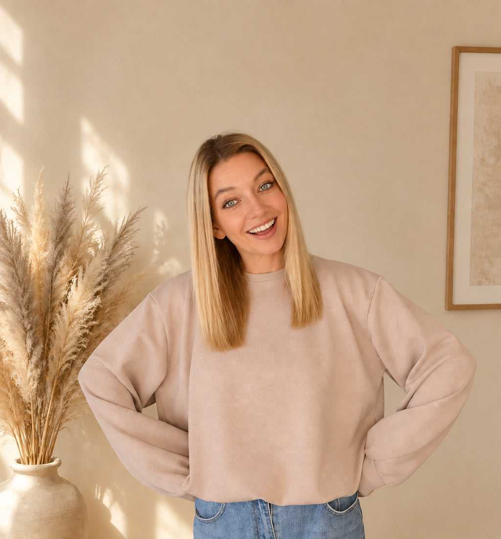 Locker geschnittenes Damen-Sweatshirt in Beige mit überschnittenen Schultern, Model mit Händen an der Hüfte.