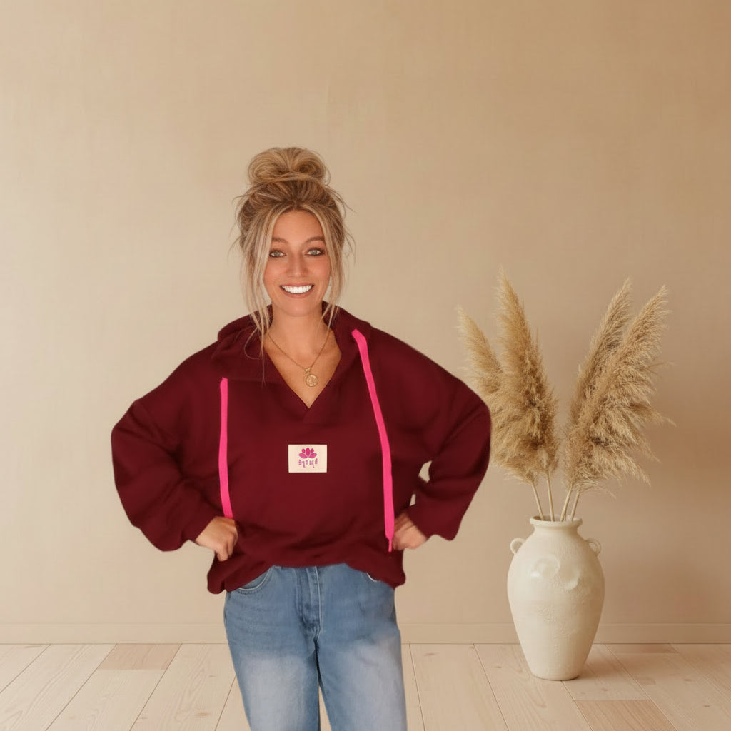Model trägt einen bordeauxfarbenen Yoga-Hoodie mit pinken Kordeln und Yoga-Lotus-Label