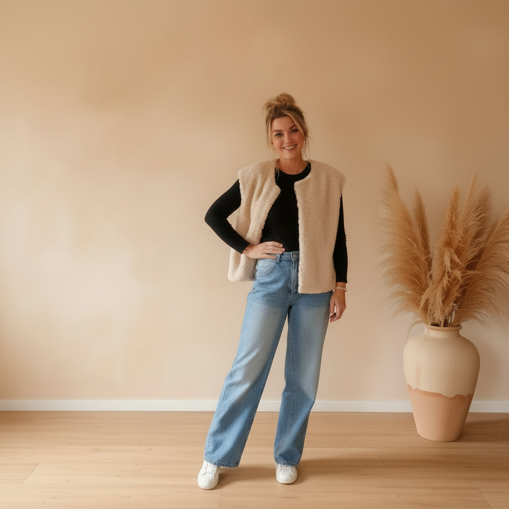 Cremefarbene Damen-Teddyfell-Weste im lässigen Ganzkörper-Look mit schwarzem Shirt, Jeans und weißen Sneakern