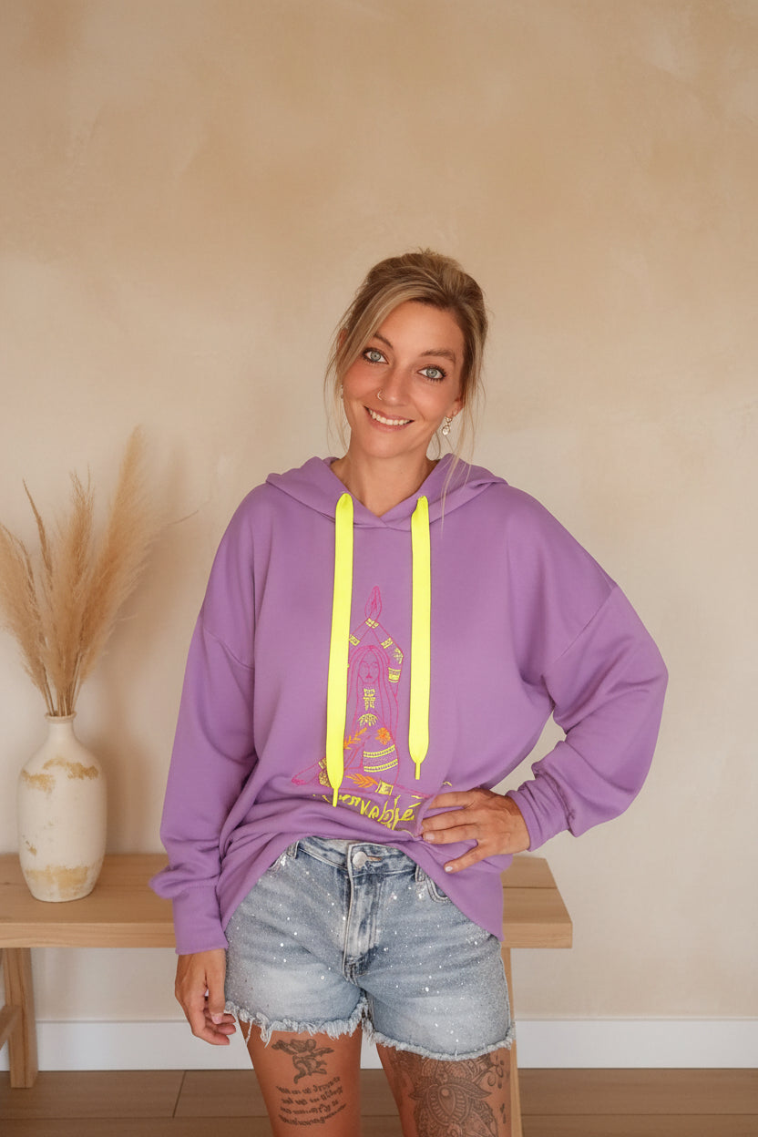 Boho-Luxe lila Oversize-Hoodie aus weichem Stoff mit Grafikprint und hellen Jeans-Shorts.
