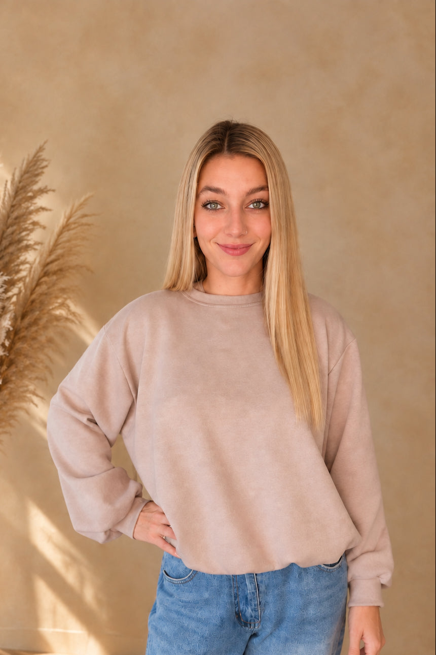 Beiges Damen-Sweatshirt mit Rundhalsausschnitt und weiten Ärmeln, frontal mit einer Hand an der Hüfte.