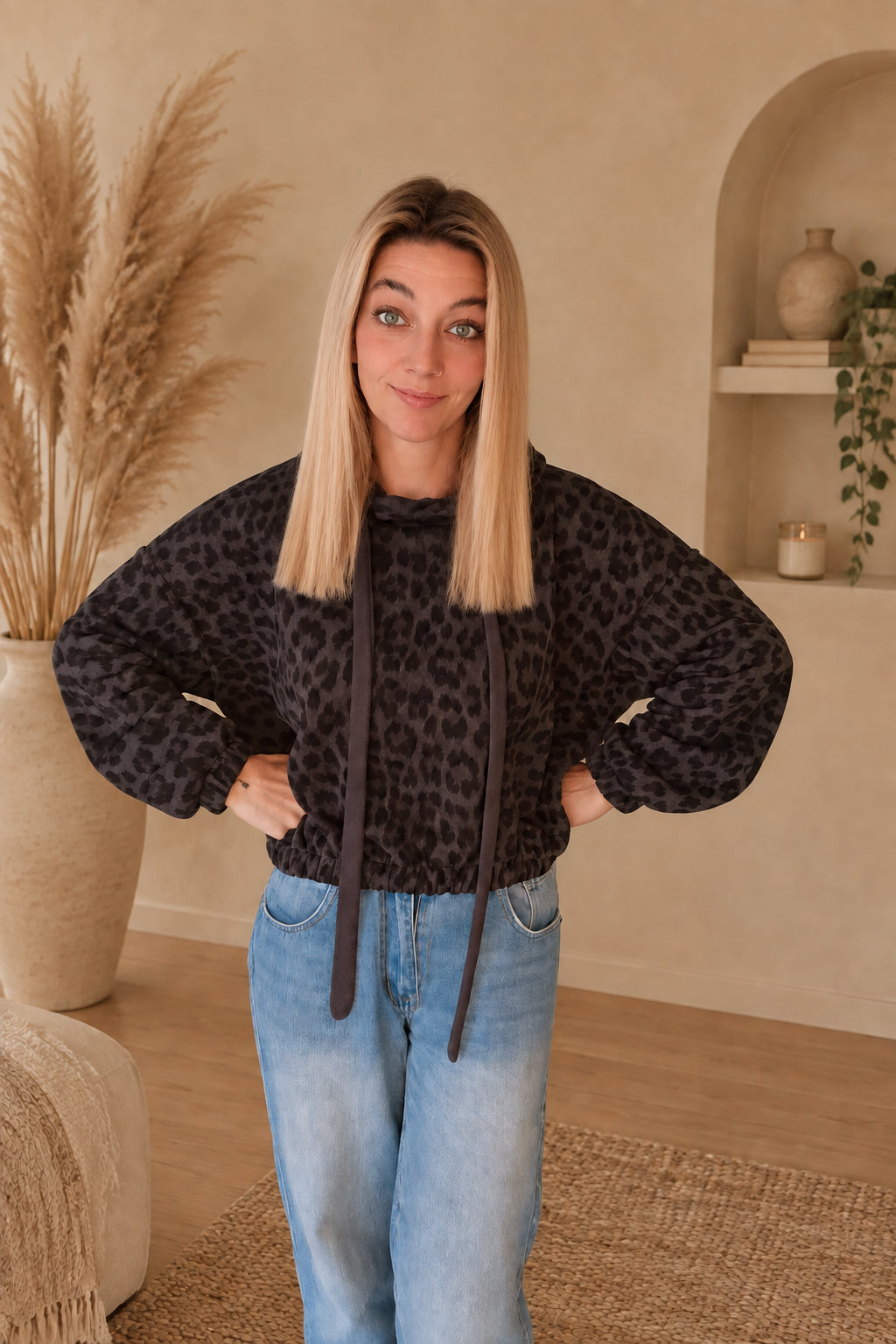 Damen-Leo-Hoodie mit weiten langen Ärmeln und kurzem gerafftem Saum, am Model mit Händen an der Hüfte.