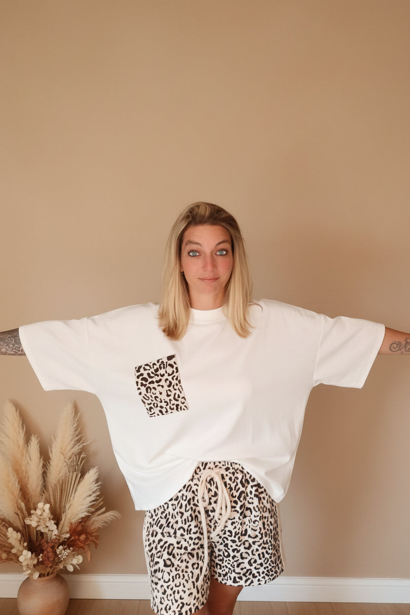 Boho-Luxe Outfit: Weißes Oversize-T-Shirt mit Leopardenprint-Tasche und passenden Shorts.