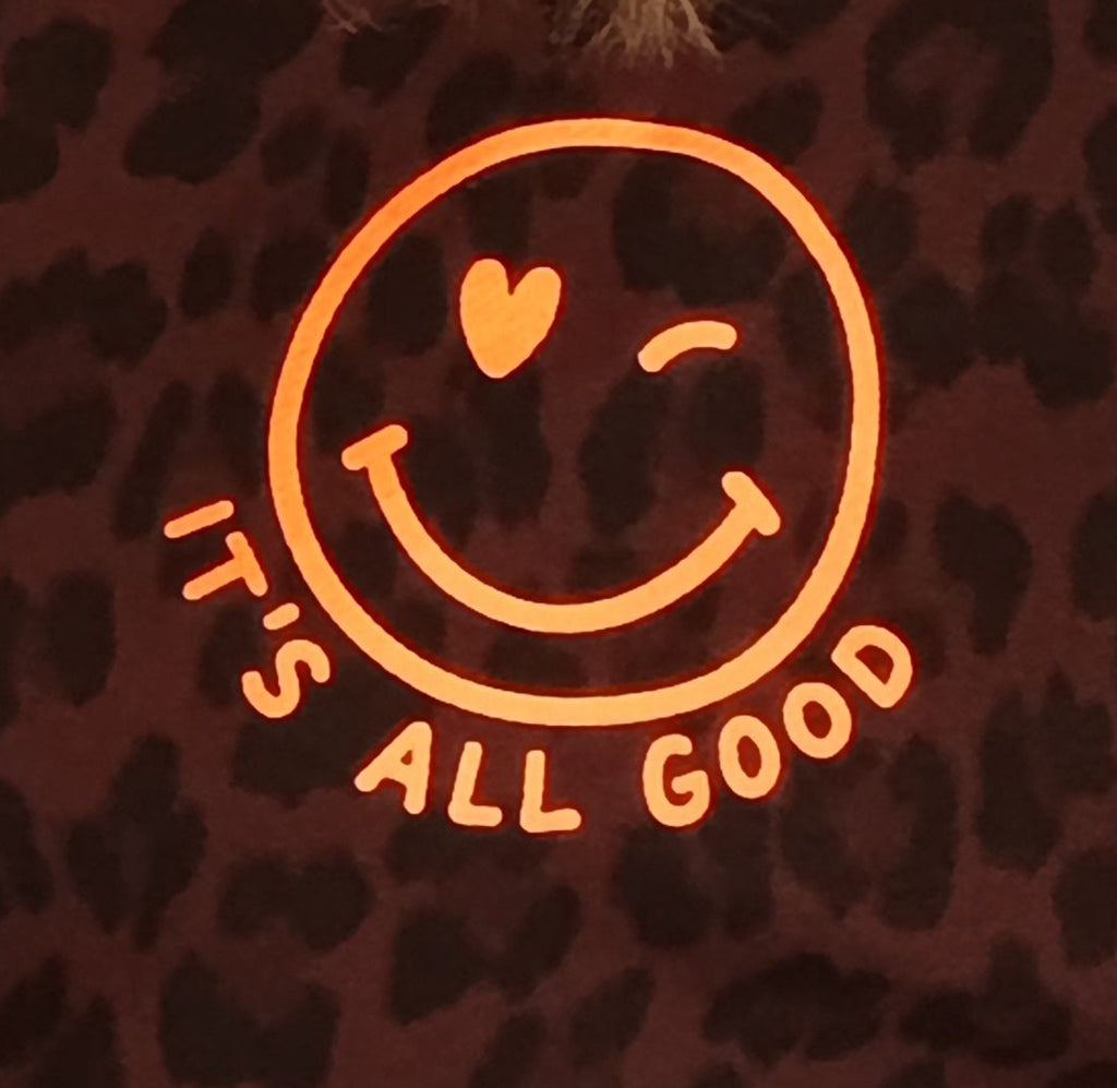 Detail-Shot Smiley Print – It's All Good oranges Logo auf dunkelbraunem Leo-Print Stoff