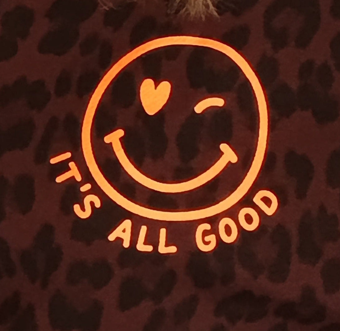 Detail-Shot Smiley Print – It's All Good oranges Logo auf dunkelbraunem Leo-Print Stoff