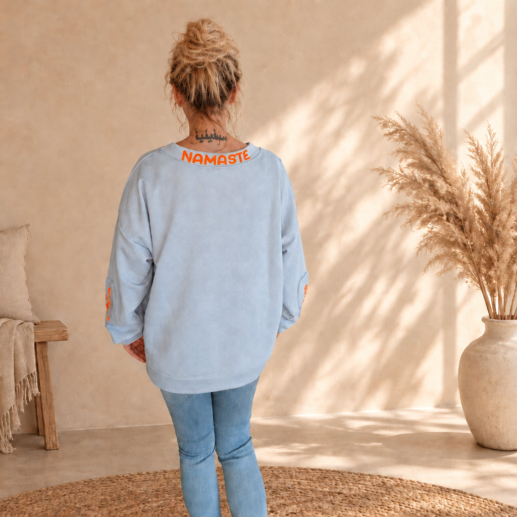 Rückansicht des hellblauen Namaste-Pullovers mit orangefarbenem Schriftzug am hinteren Ausschnitt