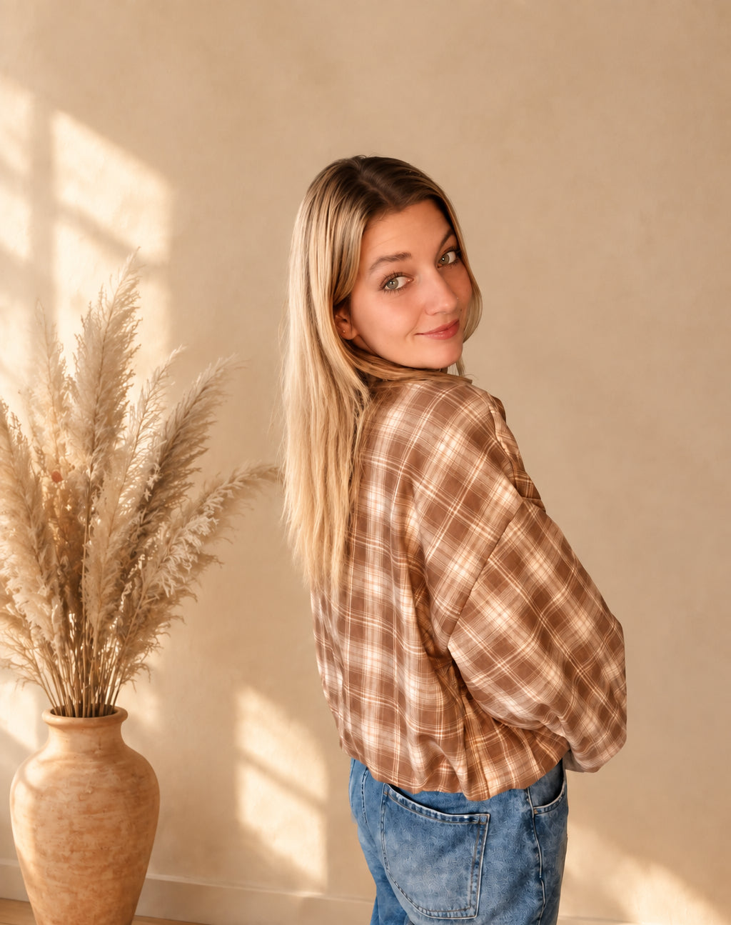 Karierte Damenjacke in Braun und Creme in schräger Rückansicht mit Blick auf die weiten Ärmel.