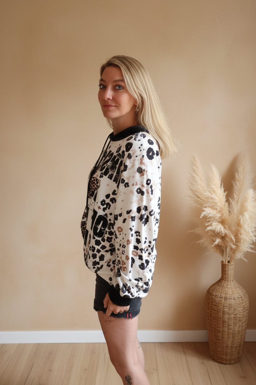 Boho-Luxe Kapuzenpullover mit Leopardenmuster in Creme und Schwarz aus weichem Stoff.