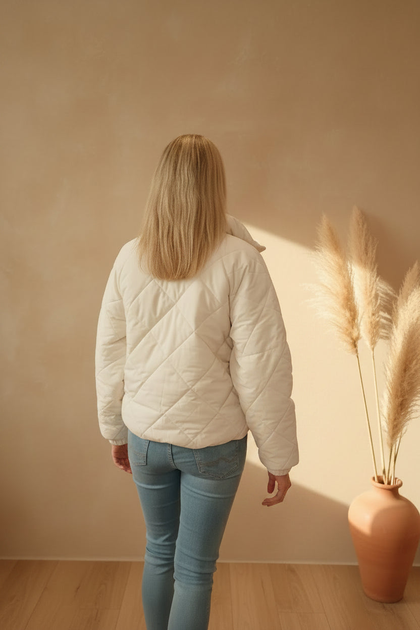 Frau in weißer Steppjacke aus Synthetik und blauer Jeans im Boho-Luxe Stil