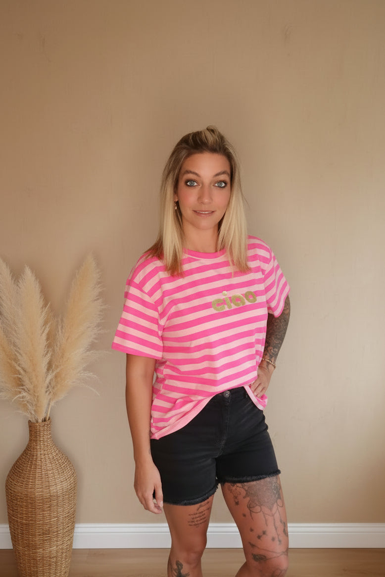 Boho-Luxe Look: Rosa gestreiftes Baumwoll-T-Shirt mit Ciao-Schriftzug und schwarze Shorts.