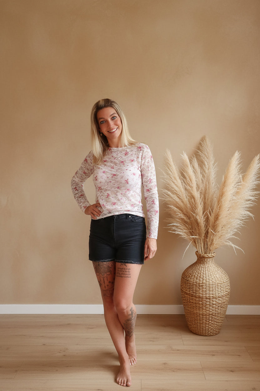 Boho-Luxe Damenmode: Florales Langarmshirt in Rosa und schwarze Denim-Shorts.