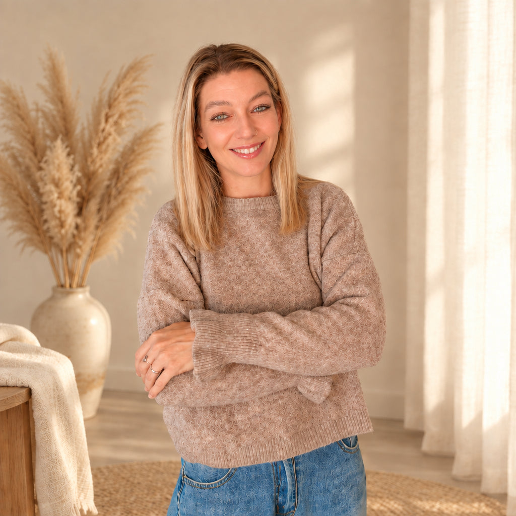 Taupefarbener Damenpullover am Model mit verschränkten Armen; Rundhalsausschnitt und Ärmel sind gut sichtbar.