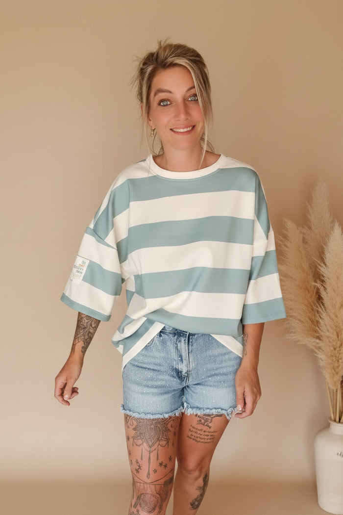 Boho-Luxe Look: Weiß-blau gestreiftes Oversize-T-Shirt aus Baumwolle und Jeansshorts.