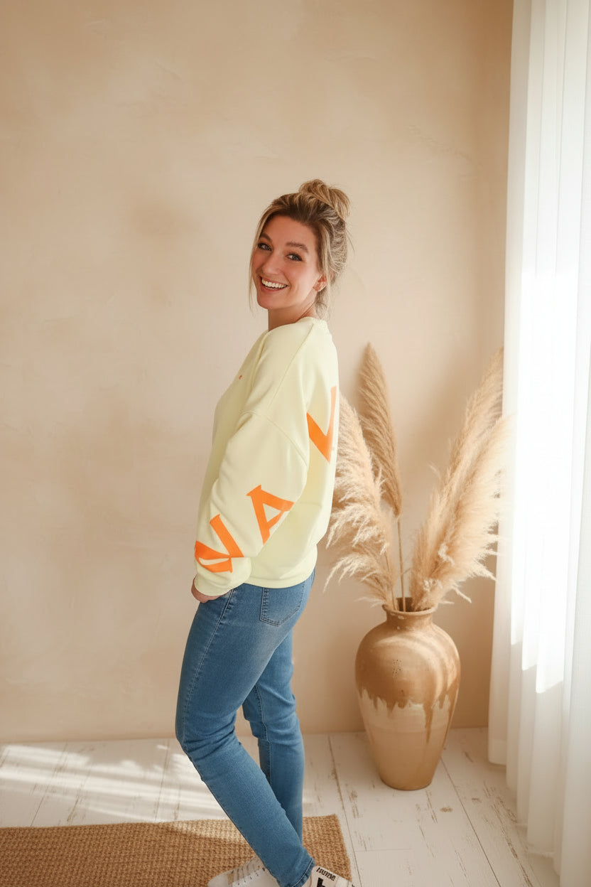 Namasté Oversize Sweatshirt Damen Pastellgelb – Seitenansicht Blick über Schulter lächelnd Neonorange Ärmelprint Pampagras