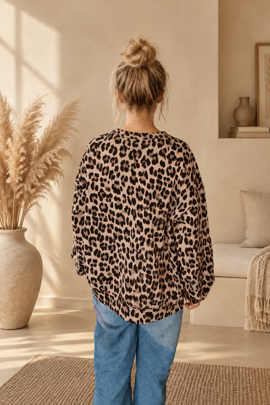 Rückansicht des Damen-Oberteils mit Leoprint, am Model mit Dutt, gesenkten Armen und vollständig sichtbarem Saum.