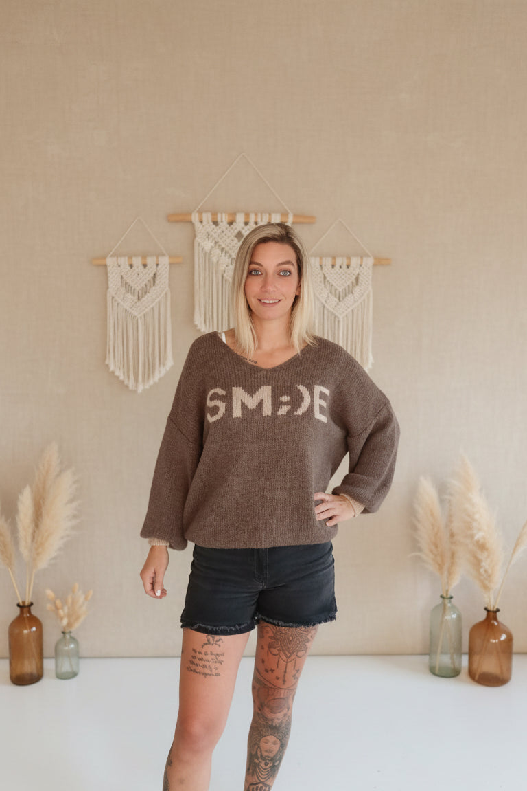 Boho-Luxe brauner Strickpullover mit Print und schwarzen Shorts.