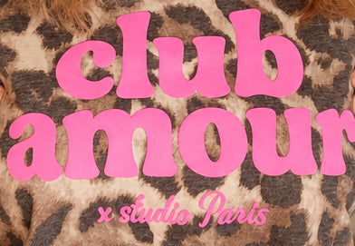 Nahaufnahme des pinken „club amour x studio paris“-Schriftzugs auf dem Leo-Print.