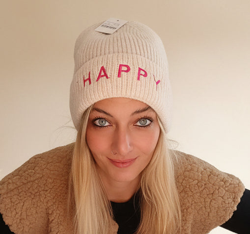 Cremefarbene HAPPY Beanie für Damen im Stricklook, getragen mit schwarzem Oberteil und Jeans