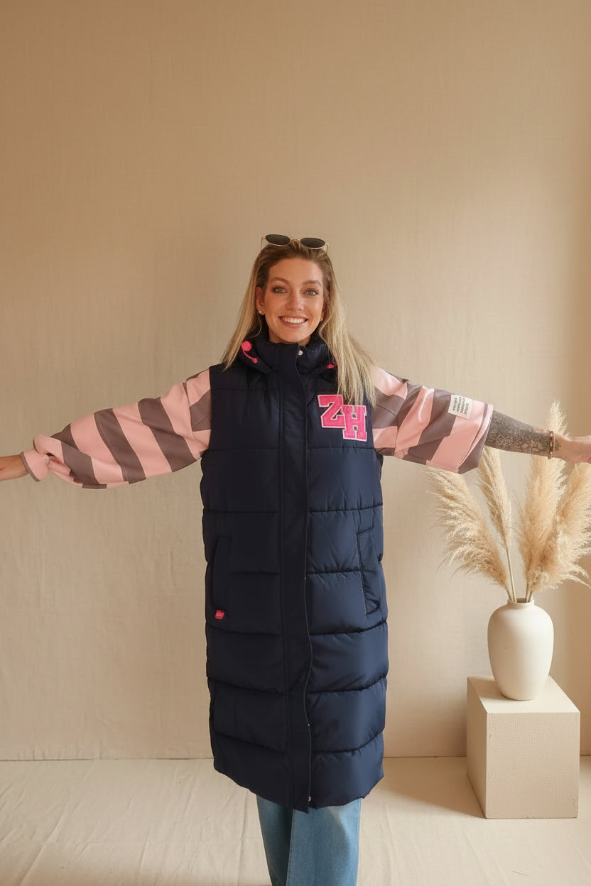 Frau in einer dunkelblauen Steppjacke mit rosa-grauen gestreiften Ärmeln im Boho-Luxe Style.