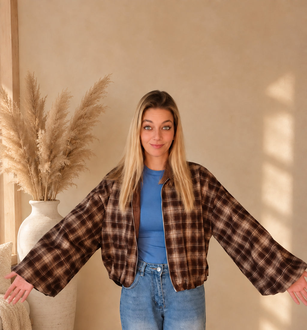 Karierte Damenjacke in Dunkelbraun und Beige mit seitlich ausgestreckten Armen zur Darstellung der Ärmelweite.