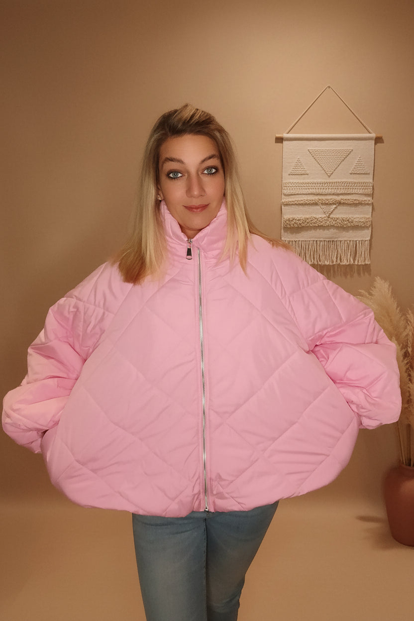 Frau in einer extragroßen, gesteppten Boho-Luxe Steppjacke in Rosa aus glänzendem Material.